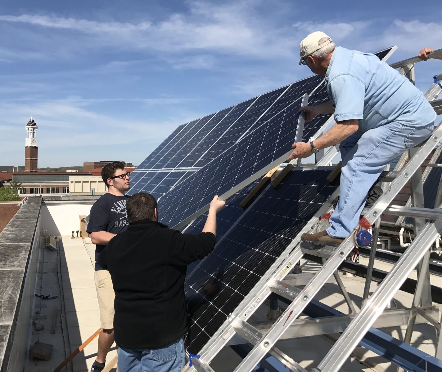 Students hand off a new solar panel on Knoy's rooftop
