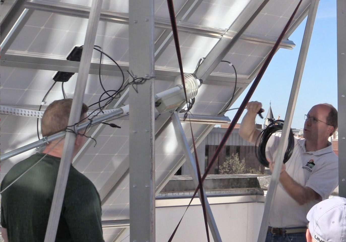 Bill Hutzel (right) discusses the new array's plug-and-play electrical connections with the installation team