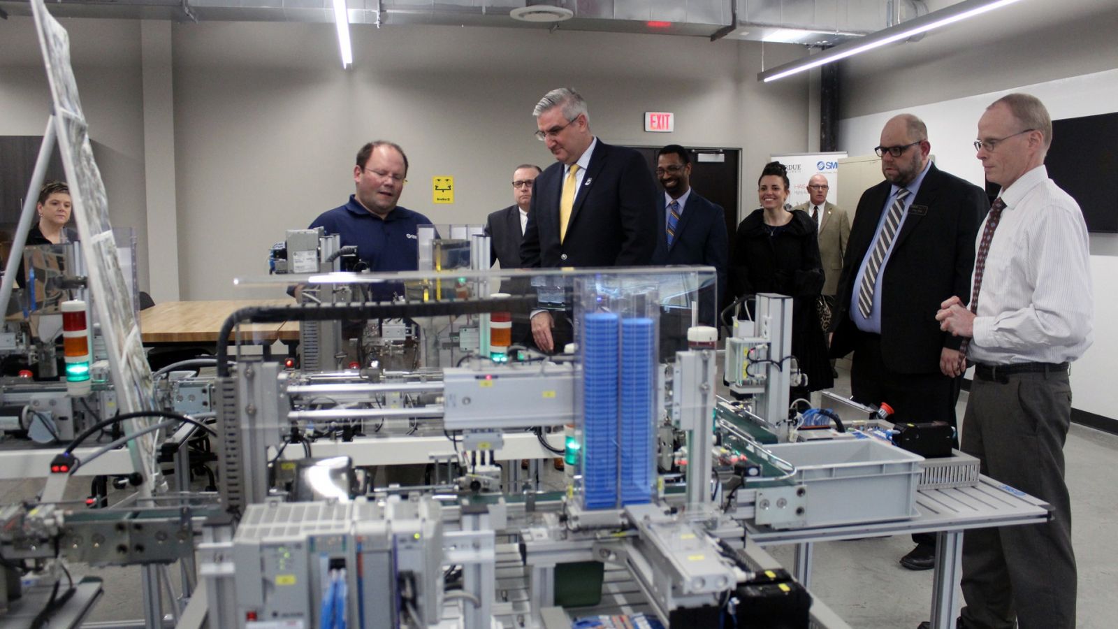 Indiana Governor Holcomb (center) talks with John Wardwell (left), national training manager at SMC Corporation, Corey Sharp (second from right), director of Purdue Polytechnic Anderson, and John Halverson (far right), director of marketing at SMC Corporation, about the SMC HAS 200, a key training system for mechatronics engineering technology students. (Photo courtesy Office of Gov. Holcomb)