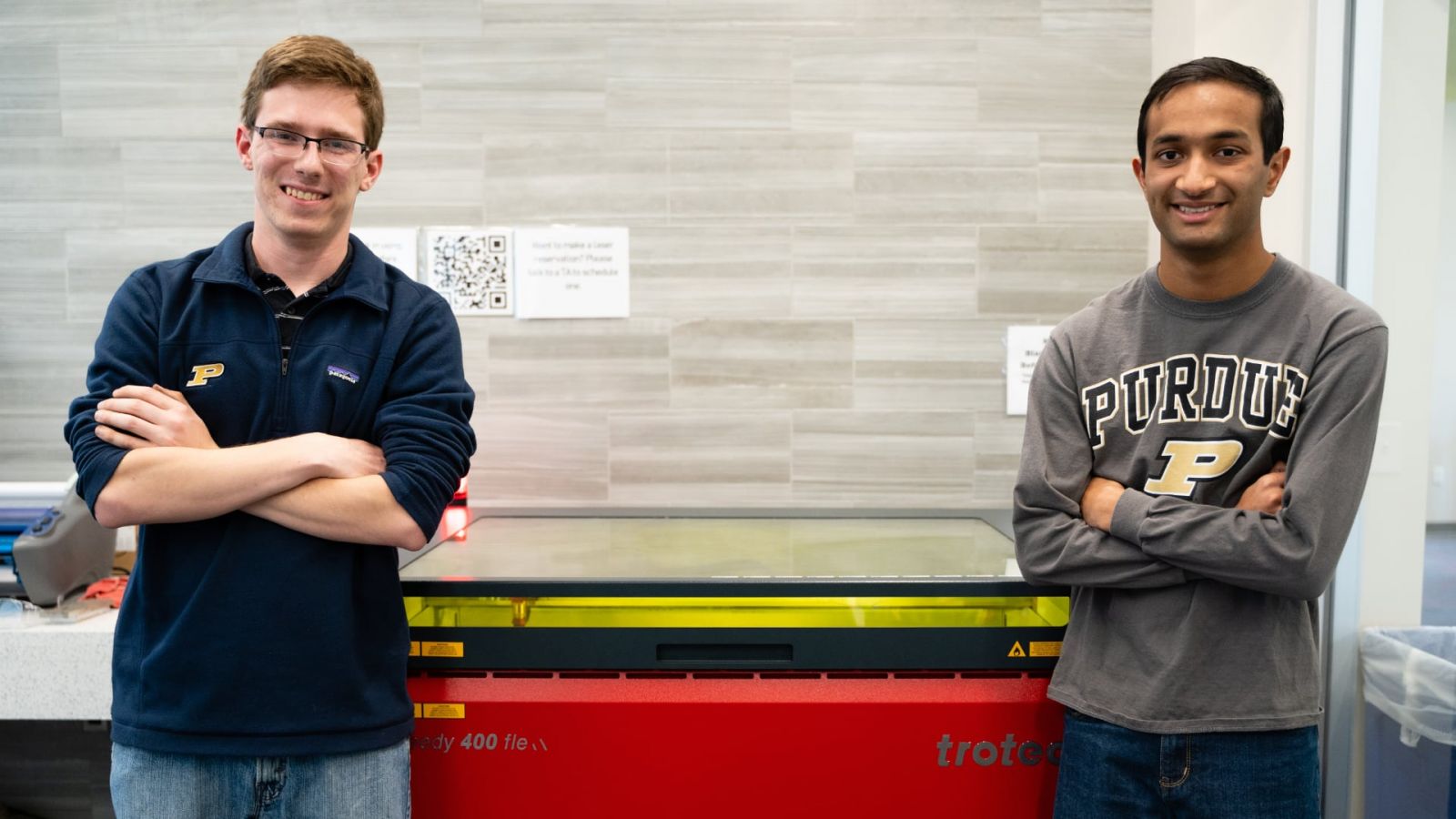 Purdue University students Matthew Fitzgerald and Shiv Patel stand before a laser engraver at the Bechtel Innovation Design Center. The students engraved 36 bookends to commemorate the historic Lafayette Street Railway. (Nick Wang/Purdue Foundry)